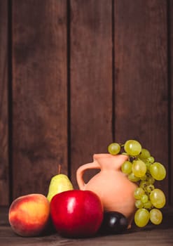 Still life with fruits and pitcher on the wooden table