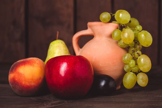 Still life with fruits and pitcher on the wooden table