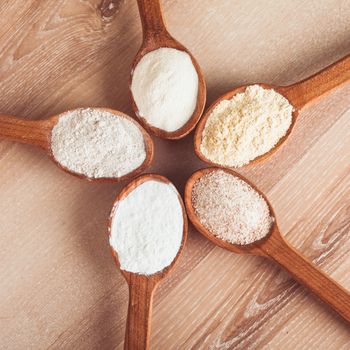 Various types of flour in five wooden spoons