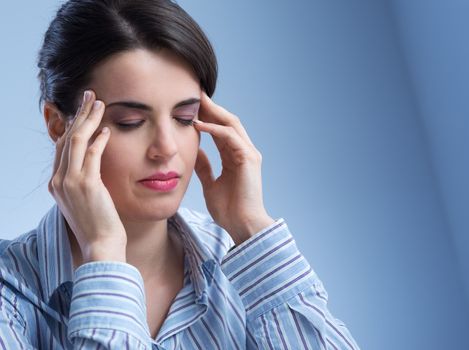 Young woman with headache touching her temples.