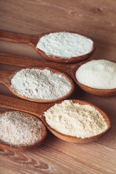 Various types of flour in five wooden spoons