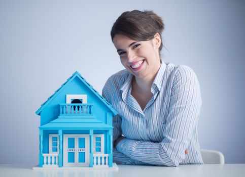 Beautiful woman at desk with light blue model house.