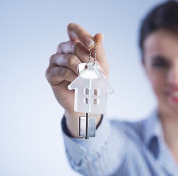 Real estate agent holding out house keys and smiling.