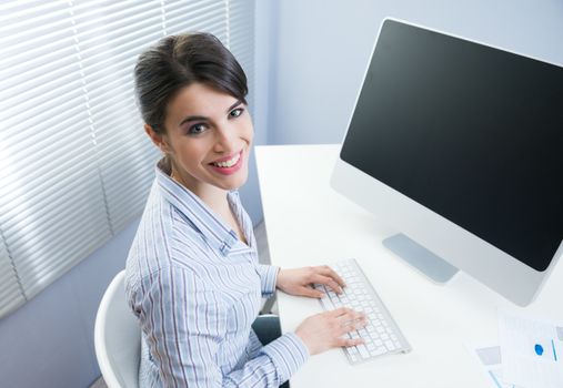 Young office worker smiling and typing on a  keyboard at office.