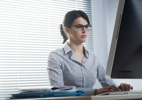 Serious confident businesswoman at desk working at computer.