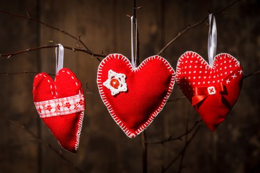 Sewed handmade red hearts on wooden background