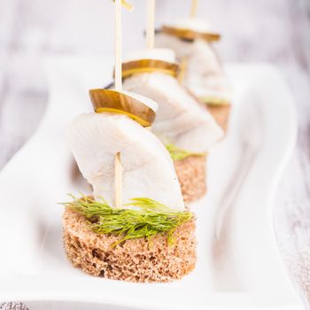 Herring canape with onion, pickled cucumber and dill