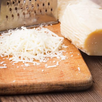 Grated Parmesan cheese with grater on a table