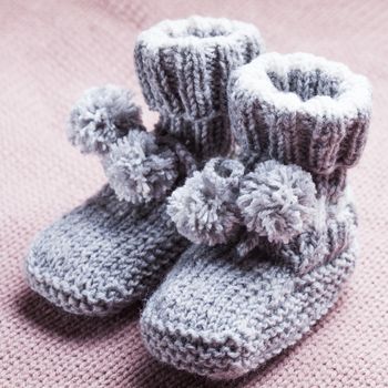 Knitted wool baby booties with pompons close up
