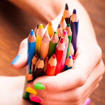 Color rainbow pencils in teenager's hands with multicoloured nails