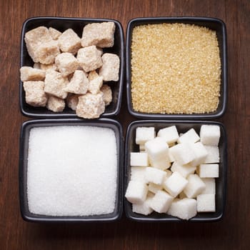 Sugar types in black bowls over the wooden background