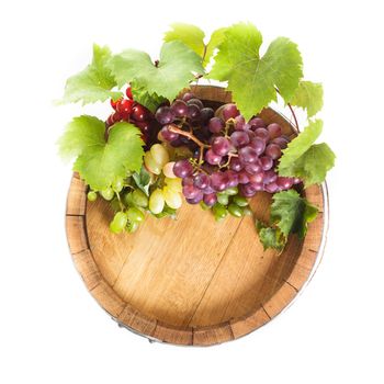 Grapes on wooden barrel with wine on a white