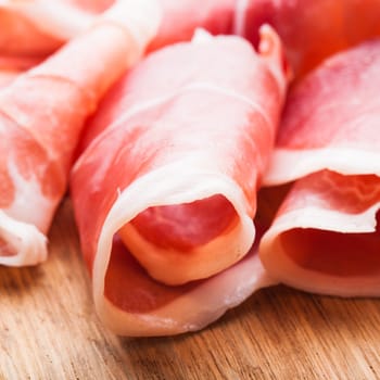 prosciutto slices close up on the wooden table