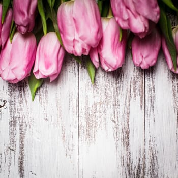 Pink tulips over shabby white wooden table