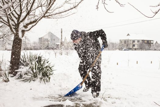 Young man remove snow near the suburban house