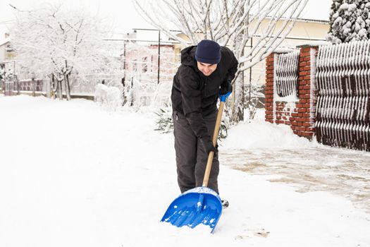 Young man remove snow near the suburban house