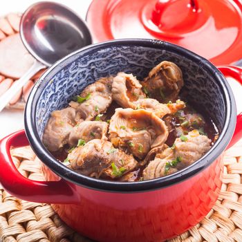 Stewed chicken gizzards in red pan on the mat