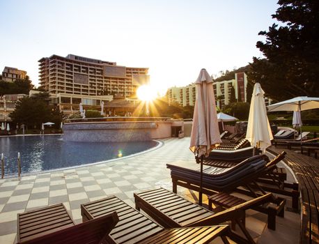 sunbeds by the pool at the hotel and sunbeams. Vocation concept. Preparations for vacationists