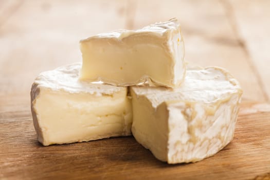 camembert cheese section on the wooden board. Macro image
