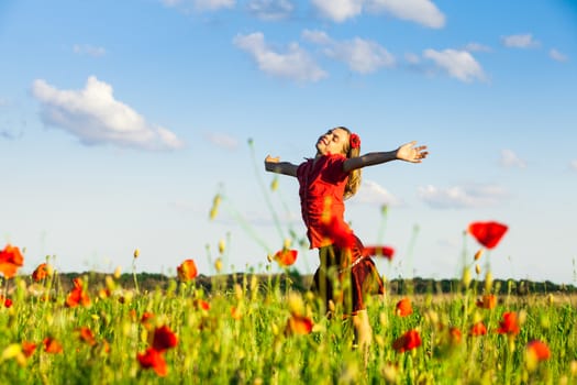 Girl stand with arms outstretched in the poppies field and enjoy the nature