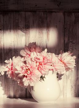 Still life with peonies over shabby wooden wall