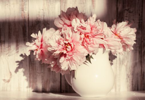 Still life with peonies over shabby wooden wall
