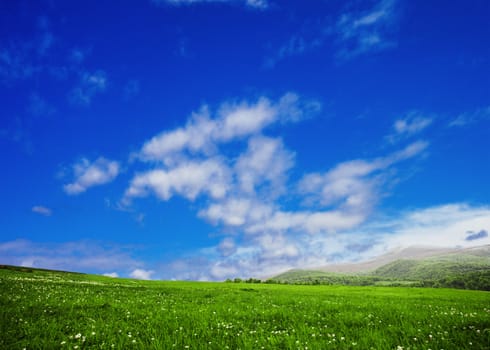 Green meadows in mountains over blue sky