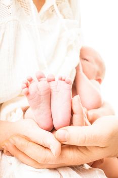 Baby breastfeeding and focus on the foots in mother and father hands