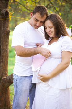 Pregnant couple with baby wear, waiting for girl. Outdoor photo