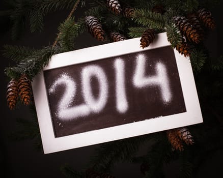 Chalkboard on the pine brach under the snow with 2014 new year