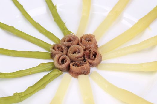Asparagus with anchovies. On a white plate.