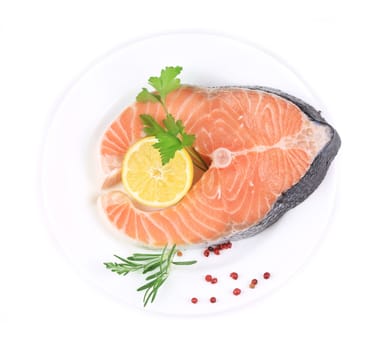 Salmon fillet with lemon and parsley. On a white plate.