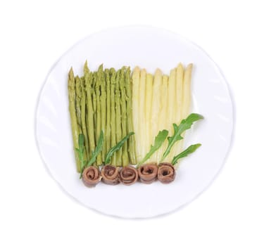 White and green asparagus with anchovies. On a white plate.