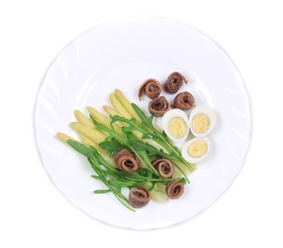 Salad with anchovies and asparagus. On a white plate.