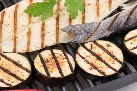close up of grilled seabass on grill with vegetables