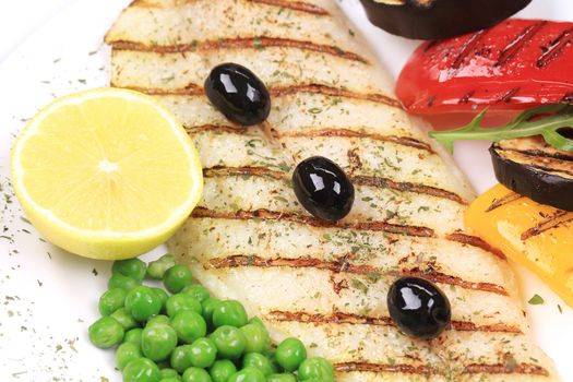Fish fillets with vegetables on barbecue. On a white plate.