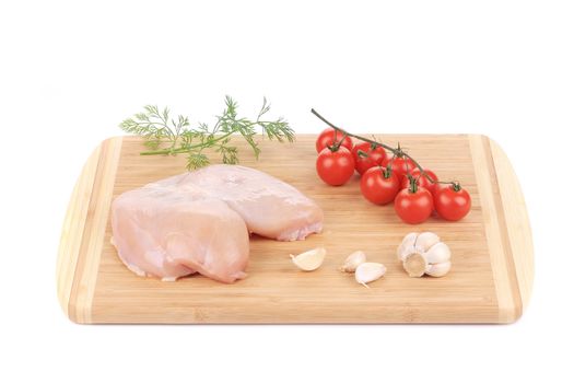 raw chicken breast with vegetables on wooden platter. Isolated on a white background