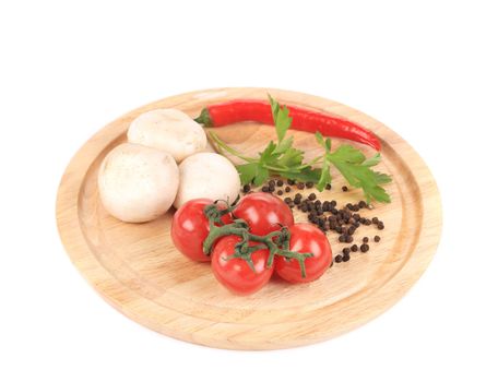 Vegetables on wooden platter. Isolated on a white background
