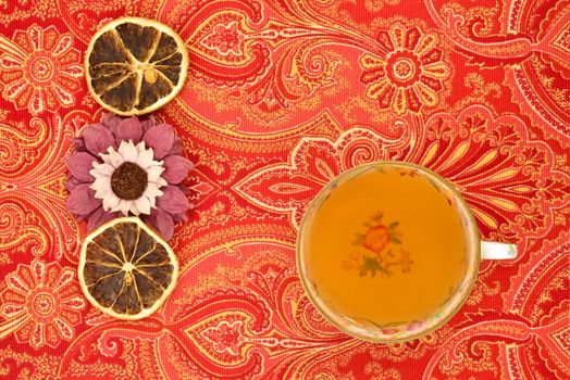 cup of herbal tea in old cup  and dried  orange on tablecloth