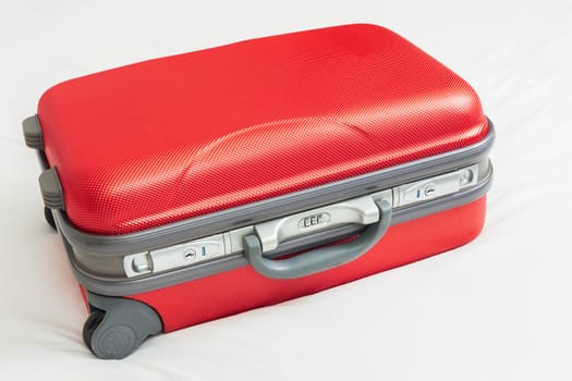 business suitcase, red color on bed for traveling
