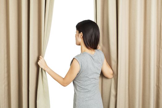 young Asian woman opening curtains