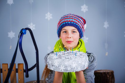 Winter Fashion. Adorable happy fashion girl in winter hat, gloves and sweater with birthday cake on birthday party.