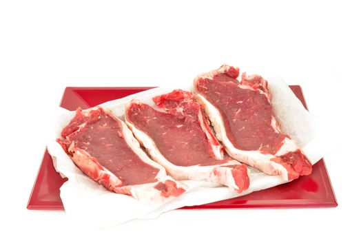 Spanish cow chops in red tray isolated on white background