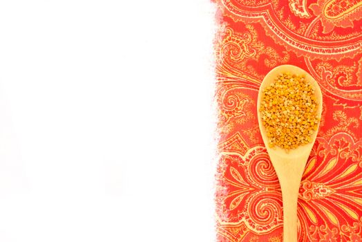 Bee pollen in wooden spoon, rustic fabric background with blank space for text