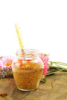 Bee pollen in glass jar and spoon upright flowers with copy space for text