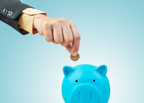 Saving money, hand putting coin into piggy bank
