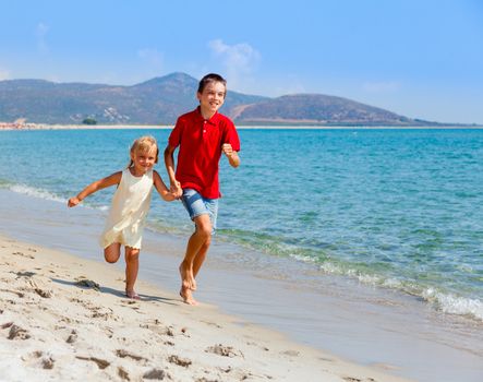 Happy children running along a beach