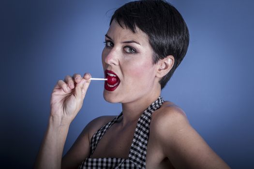 Candy, happy young woman with lollypop in her mouth on blue background