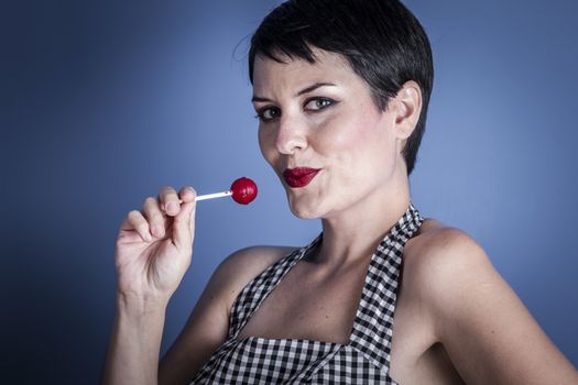 Eat, happy young woman with lollypop in her mouth on blue background