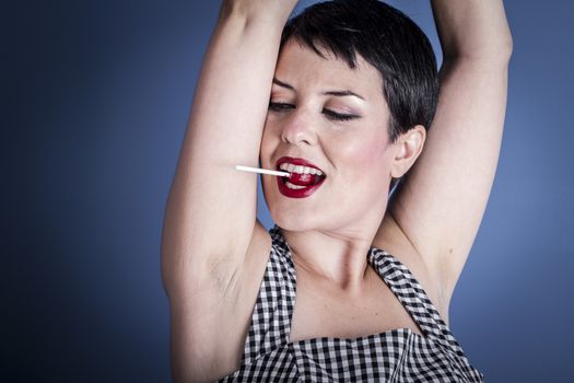Diet, happy young woman with lollypop in her mouth on blue background